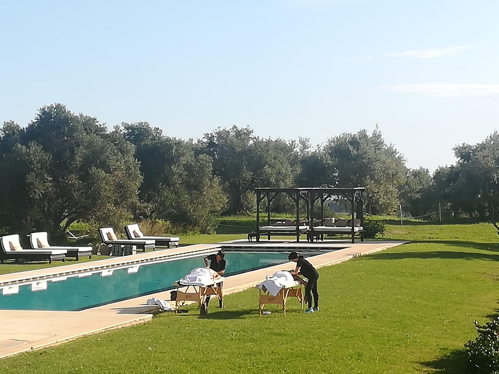 Een zwembad met ligbedden en een pergola.