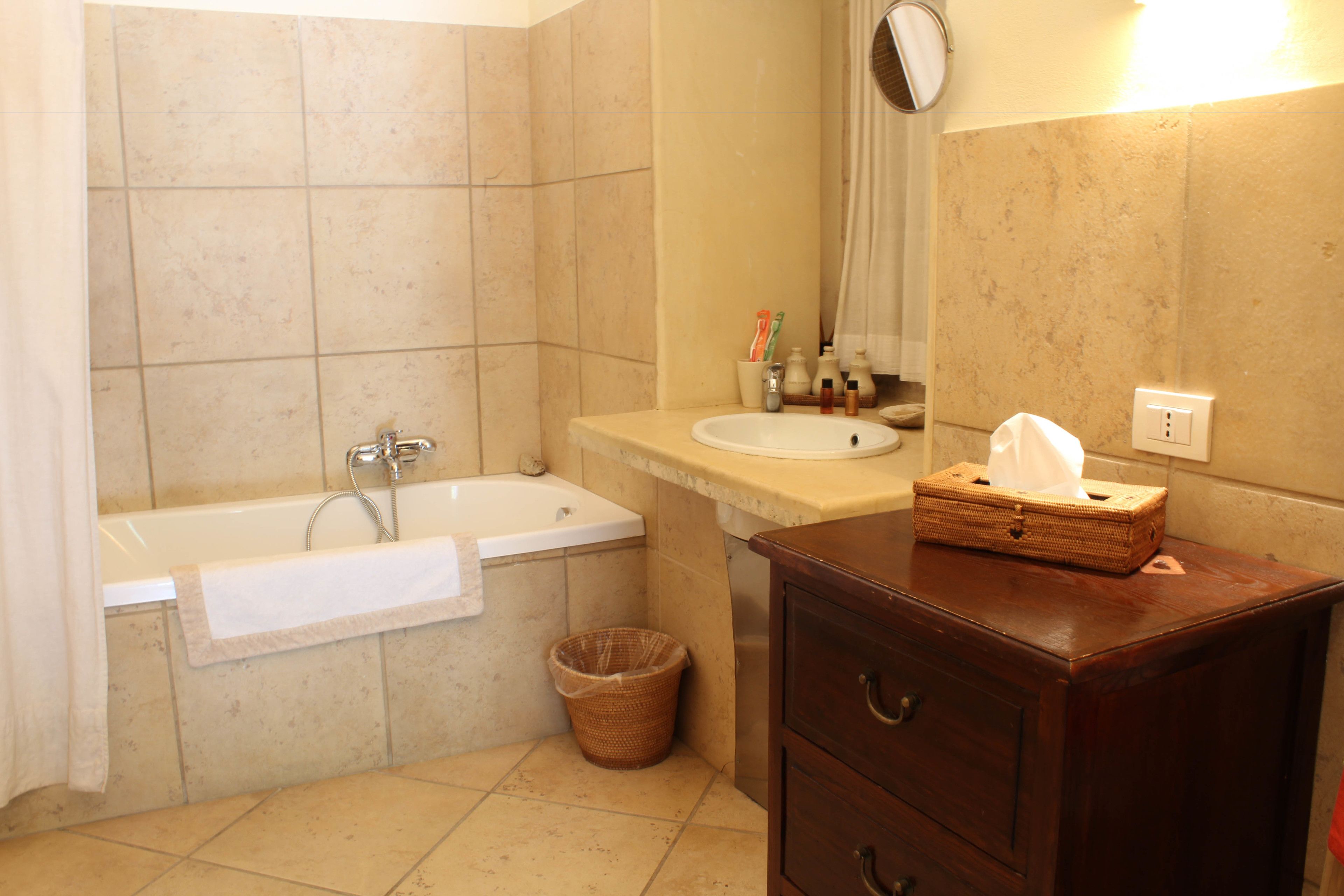 Une salle de bain avec une baignoire, un lavabo, un miroir et un meuble en bois.