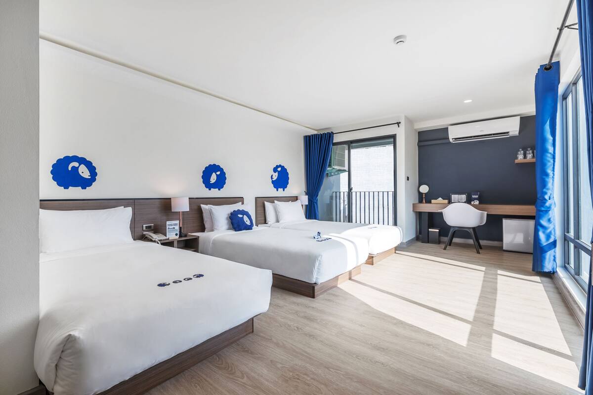 Ein Hotelzimmer mit zwei Betten, einem Schreibtisch und einem Balkon.