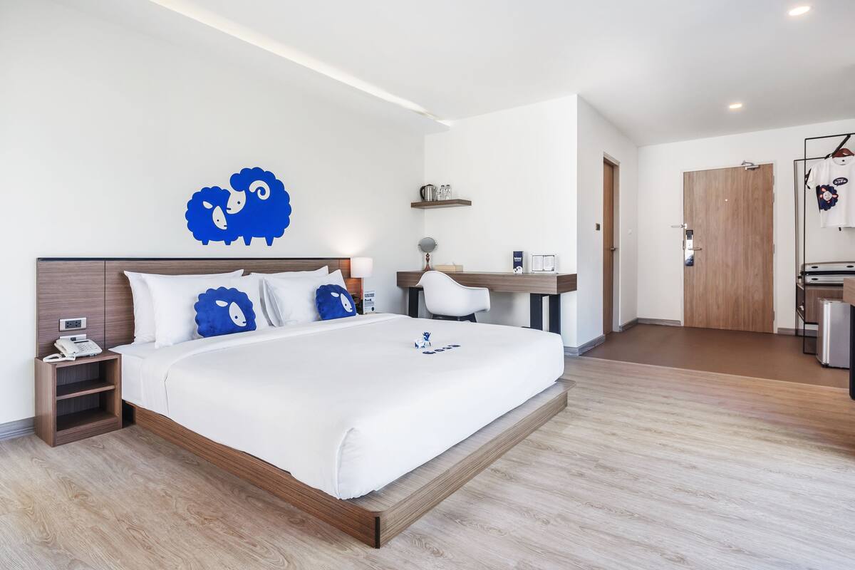 Ein modernes Hotelzimmer mit einem großen Bett, einem Schreibtisch und einem Kleiderschrank.