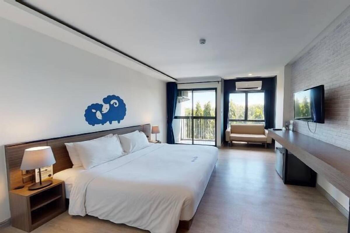 Ein modernes Hotelzimmer mit einem großen Bett, einem Schreibtisch, einem Fernseher und einem Balkon mit Blick.