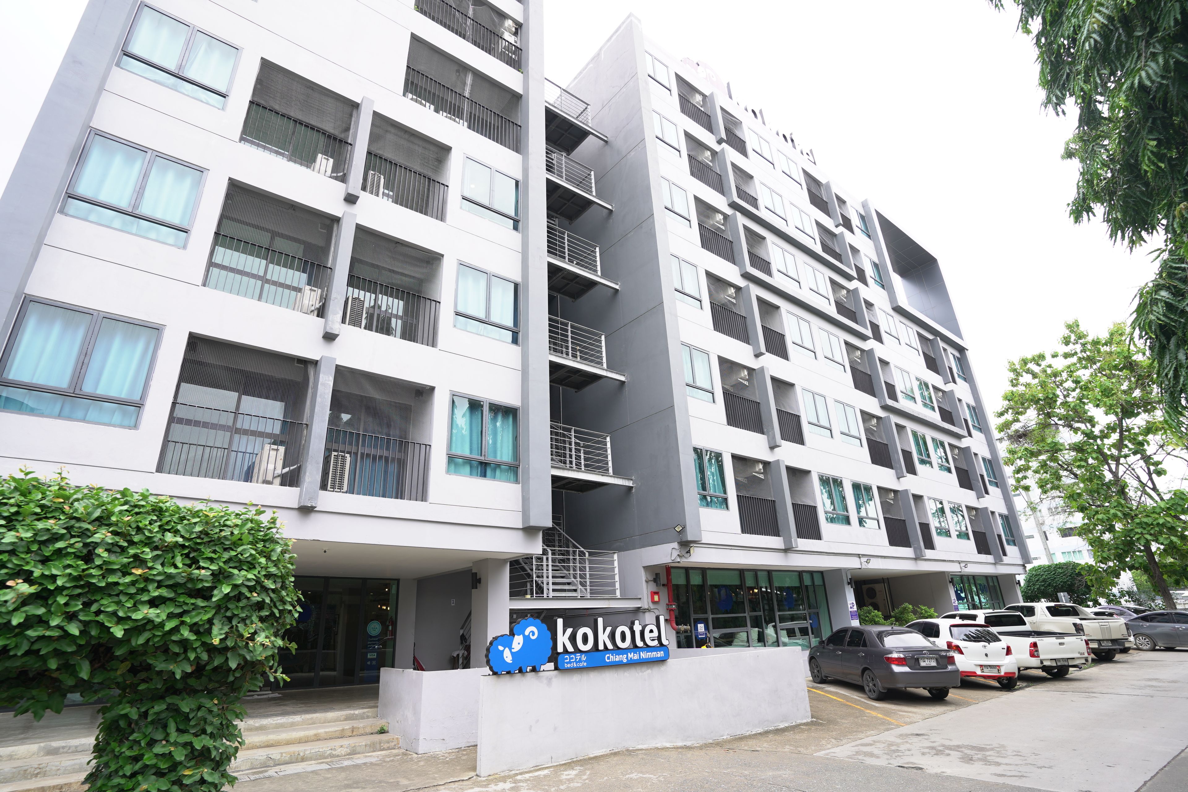 A modern building with multiple floors, balconies, and a sign for 'Kokotel'.
