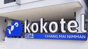 Placa para 'Kokotel' com design azul e branco, indicando uma cama e café.