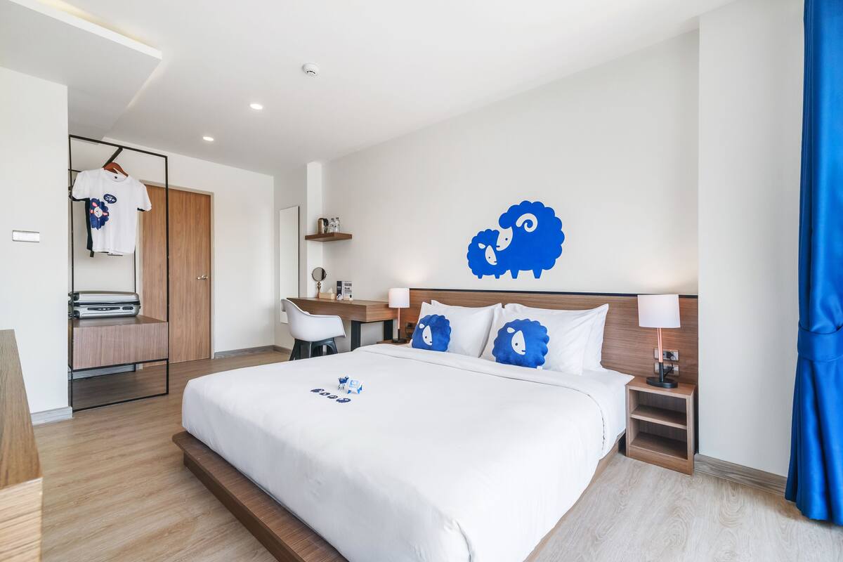 Ein modernes Hotelzimmer mit einem großen Bett, einem Schreibtisch und einem Kleiderschrank.