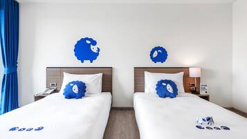 Ein Hotelzimmer mit zwei Betten, jedes mit einem blauen Kopfkissen und einer Wanddekoration.