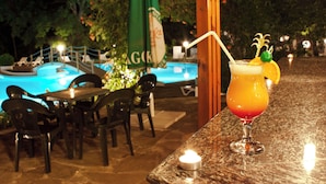 A bar area with a pool, outdoor seating, and a cocktail on the counter. - Ljuljak (Golden Sands)