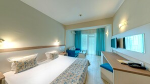 Une chambre d’hôtel comprenant un lit, un bureau avec un téléphone, une télévision et un coin salon avec un canapé et des rideaux.