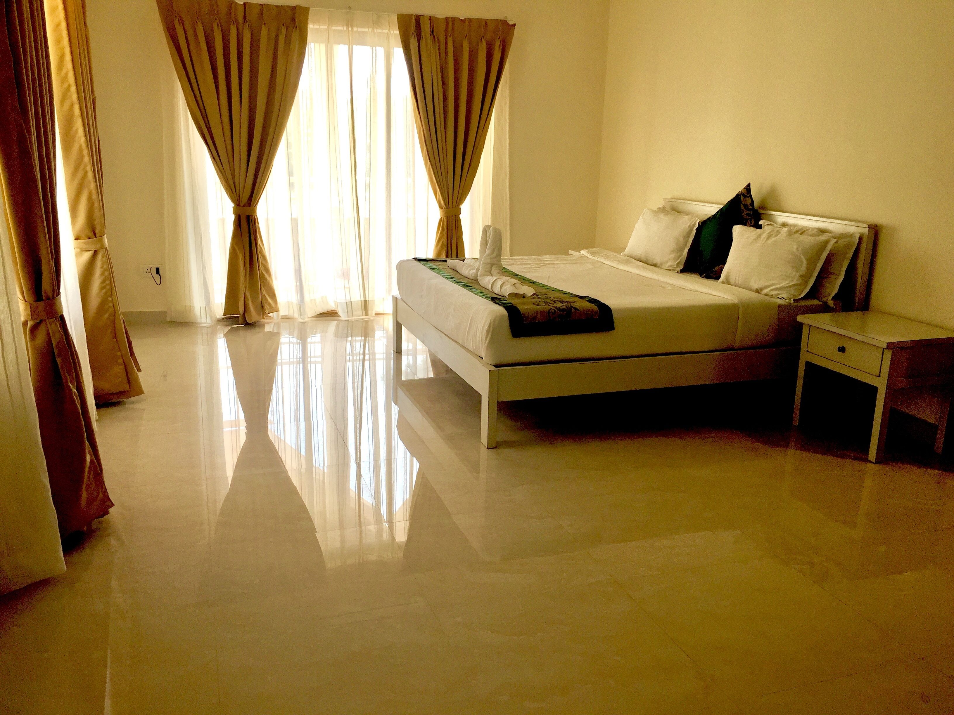 Quarto com cama, mesa de cabeceira e cortinas.