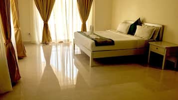 Quarto com cama, mesa de cabeceira e cortinas.