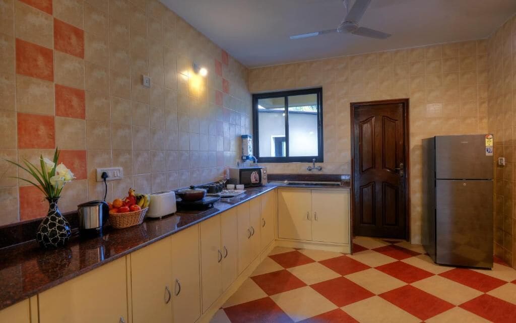 Una cocina con piso a cuadros, un refrigerador y una ventana.