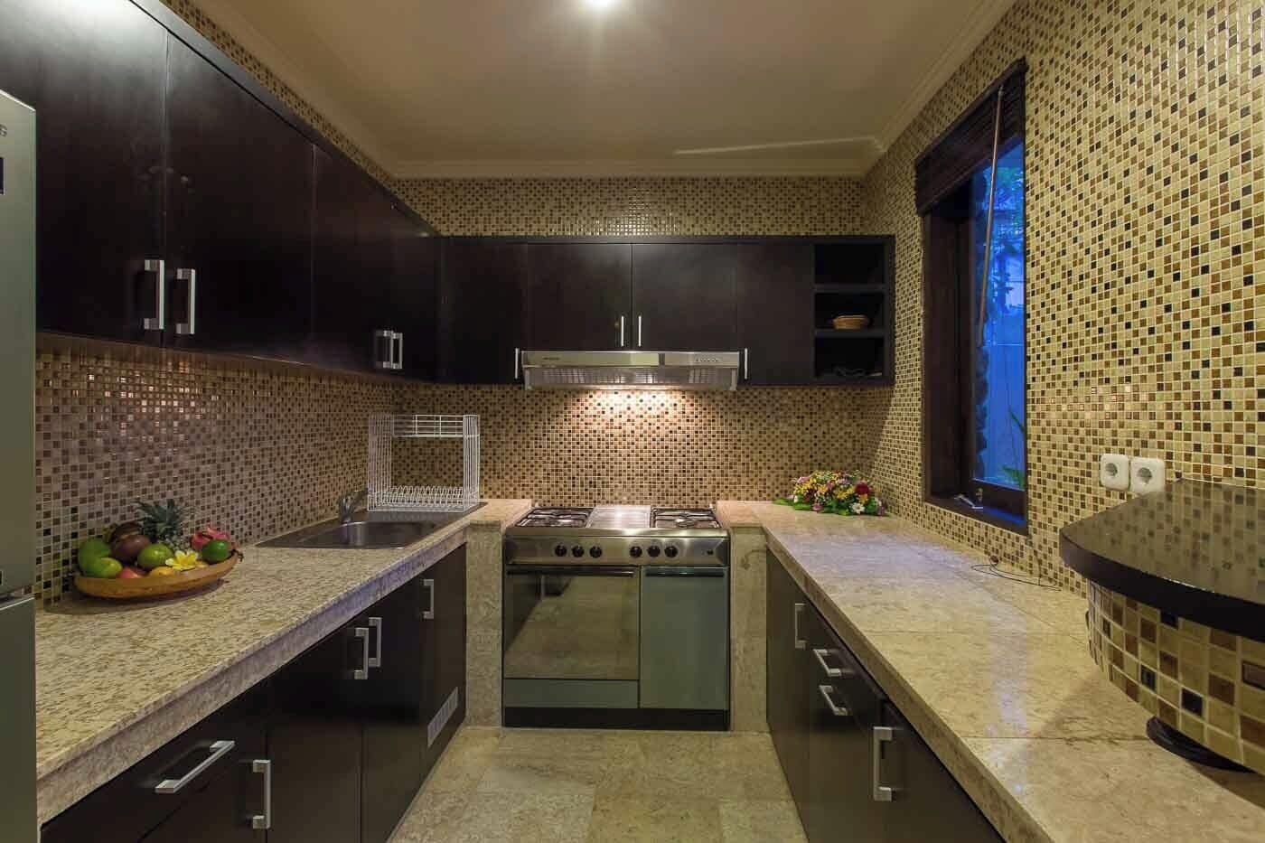 A modern kitchen with dark cabinets, a stainless steel stove, and a tiled backsplash.