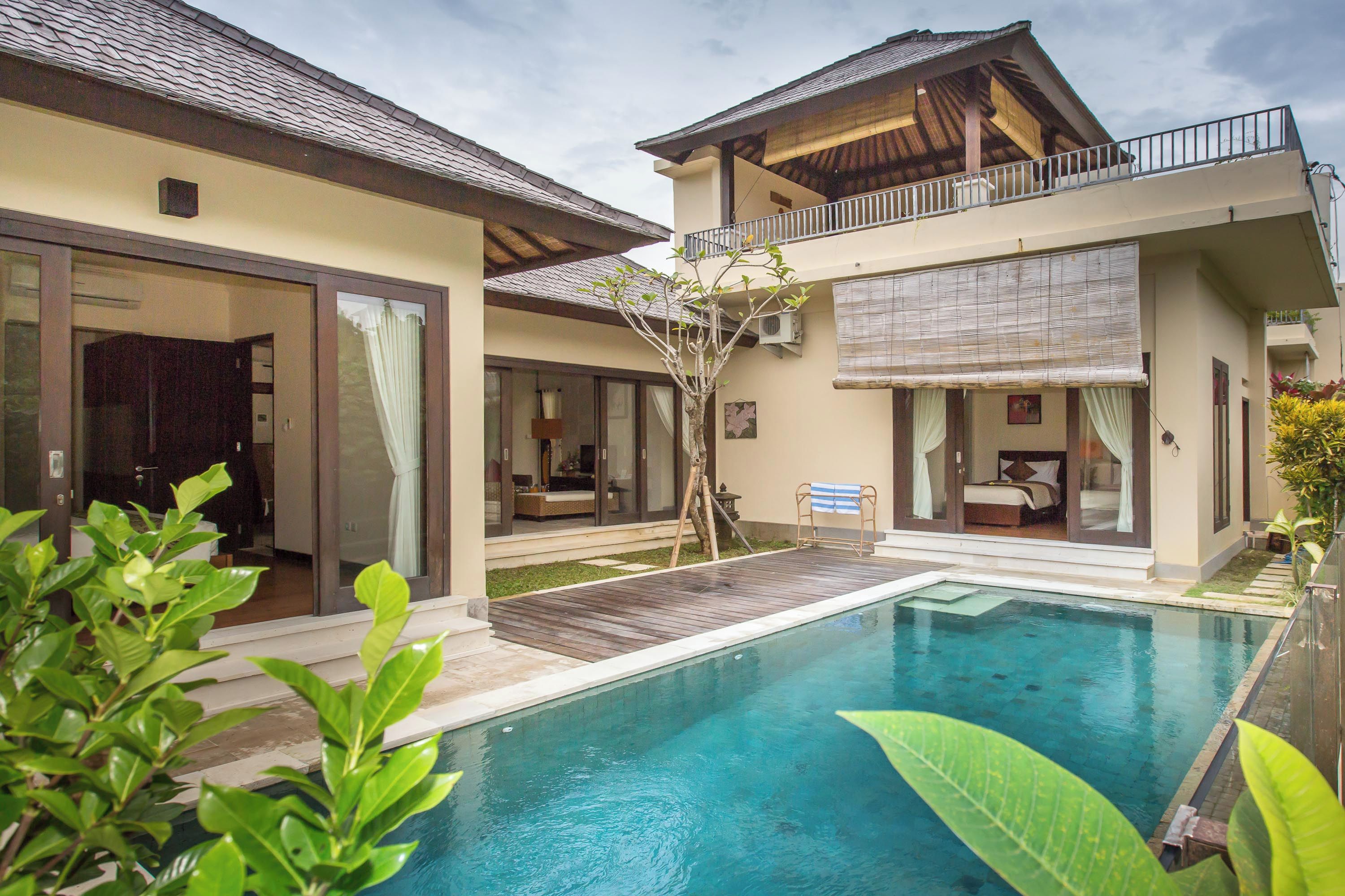 A two-story house with a swimming pool, large sliding glass doors, and a balcony.