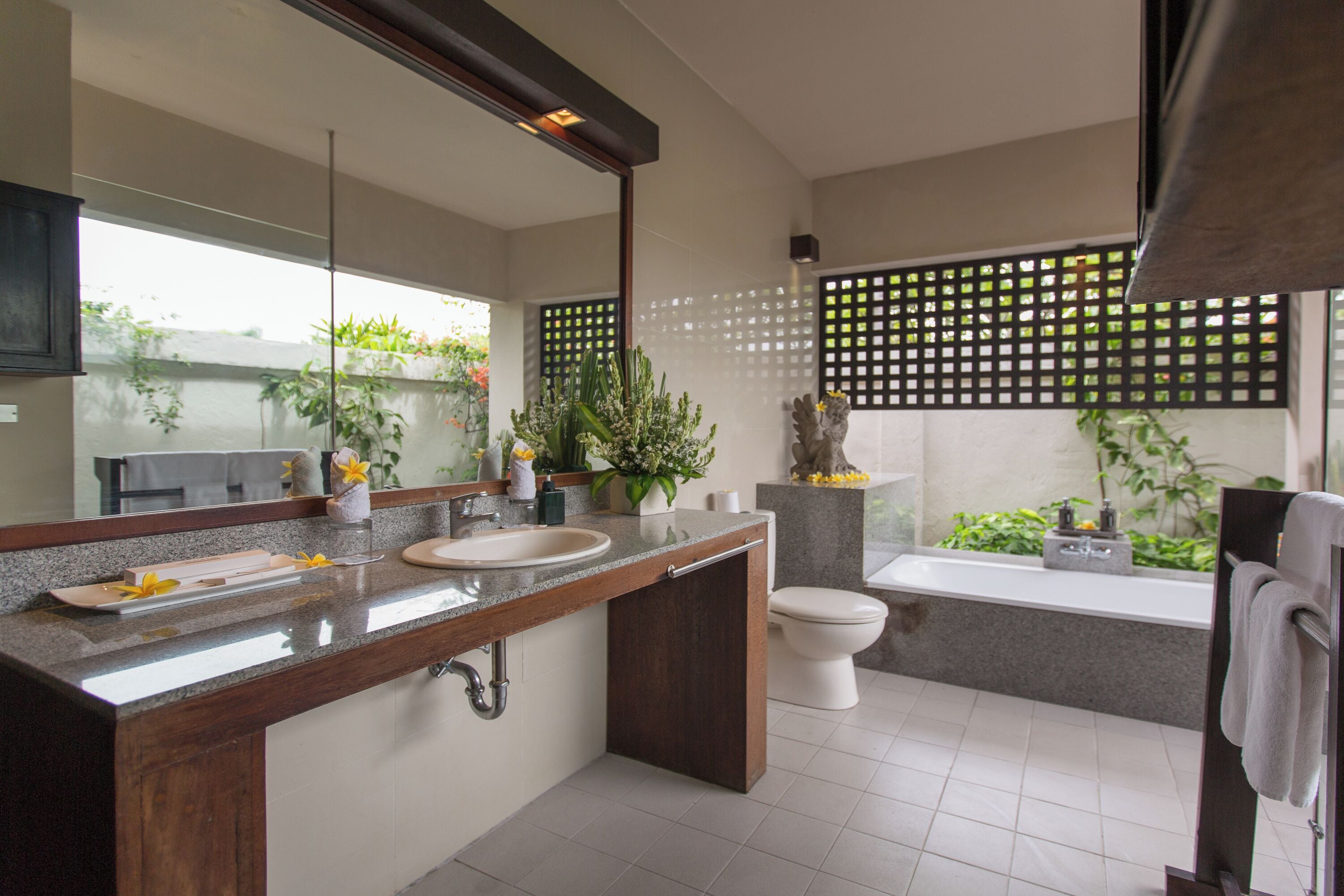 A modern bathroom with a large mirror, two sinks, a toilet, and a bathtub.