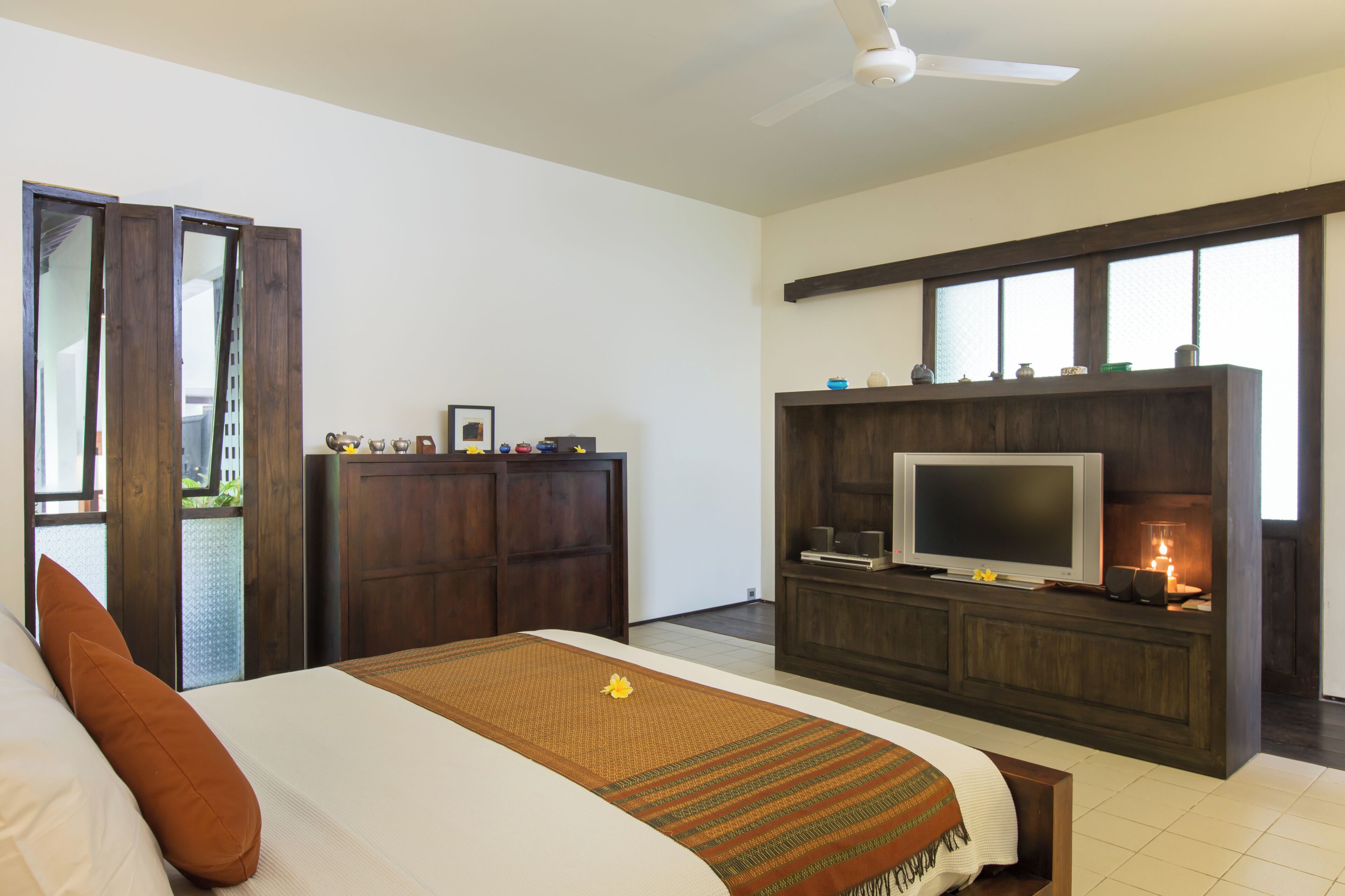 Una habitación de hotel moderna con una cama grande, televisión, un armario de madera y un balcón con vistas.