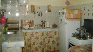 A kitchen with a gas stove, a sink, and various kitchen utensils. There is a refrigerator with decorative magnets and a microwave above it. - Appartement 2 Chambre Ville Nouvelle Fes (Fes)