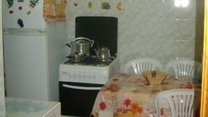 A small kitchen with a stove, refrigerator, and dining table with chairs. - Appartement 2 Chambre Ville Nouvelle Fes (Fes)