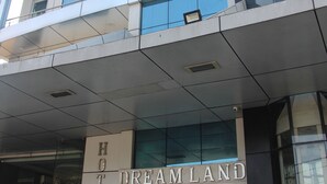 Un hotel llamado "Dreamland" con una fachada moderna, ventanas amplias y una entrada visible.