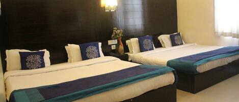 Quarto de hotel com duas camas, cada uma com cabeceira, roupa de cama branca e almofadas decorativas.
