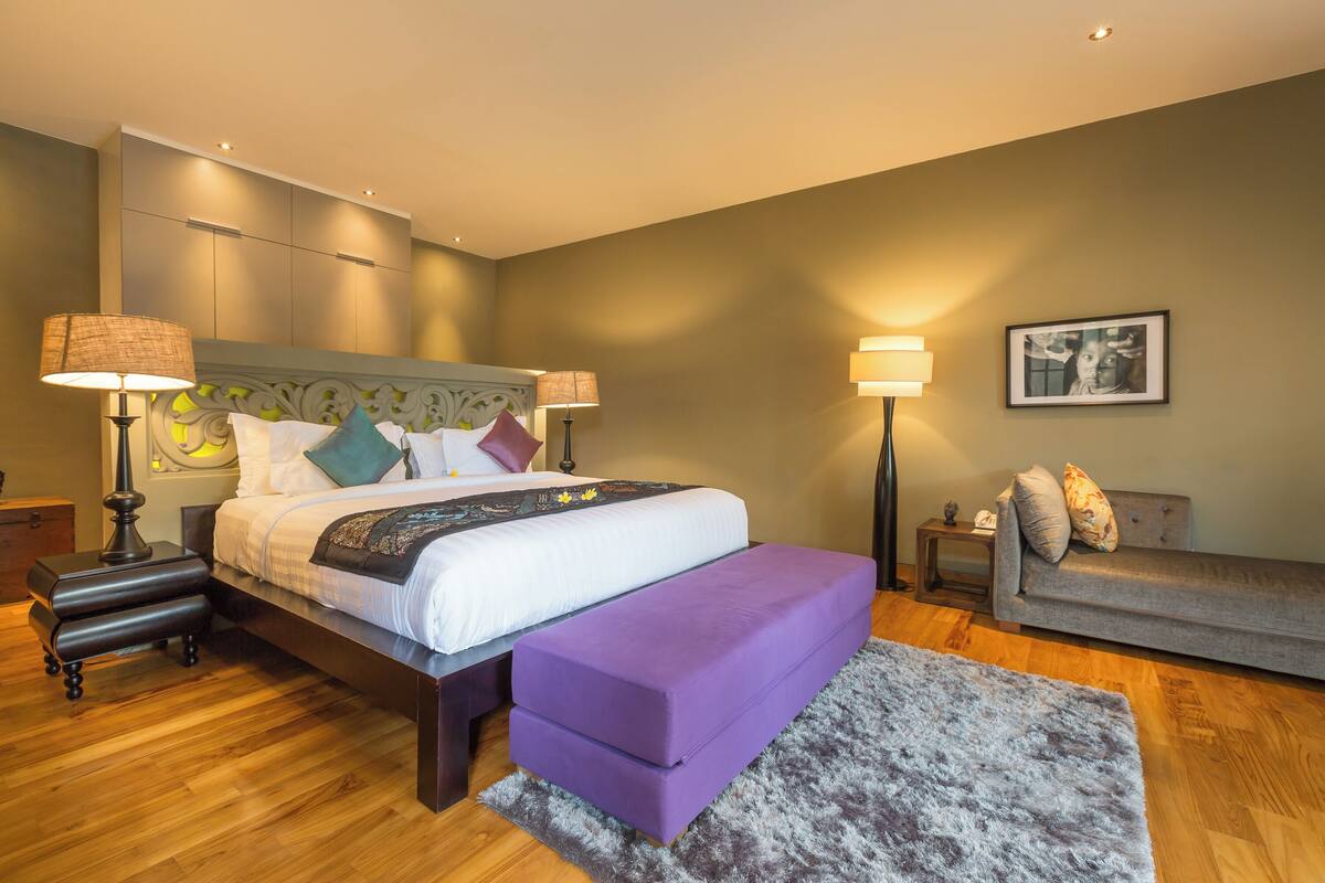 A modern bedroom with a bed, bedside tables, a bench, a sofa, and a rug.
