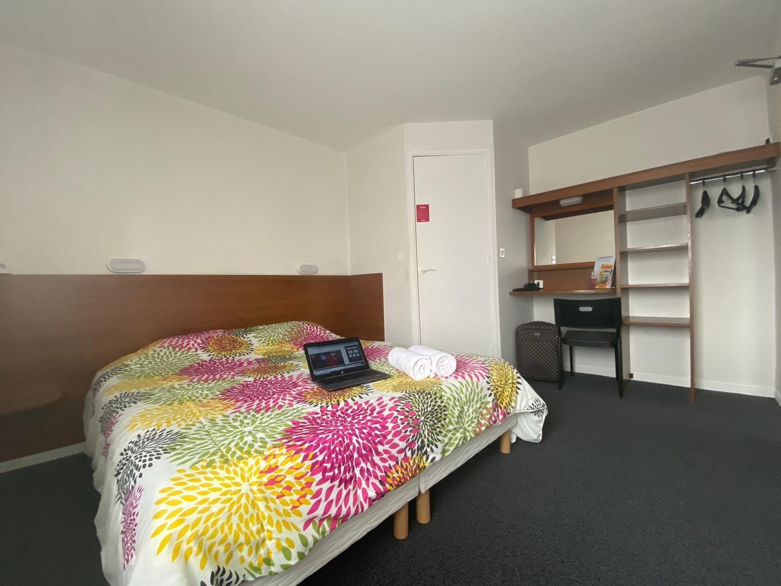 A hotel room with a bed, a desk, and a wardrobe.