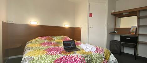 Una habitación de hotel con cama, escritorio y silla.
