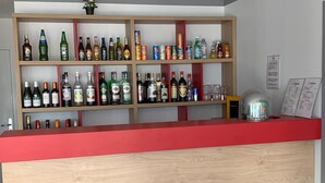 Uma área de bar com prateleiras repletas de garrafas e copos diversos.