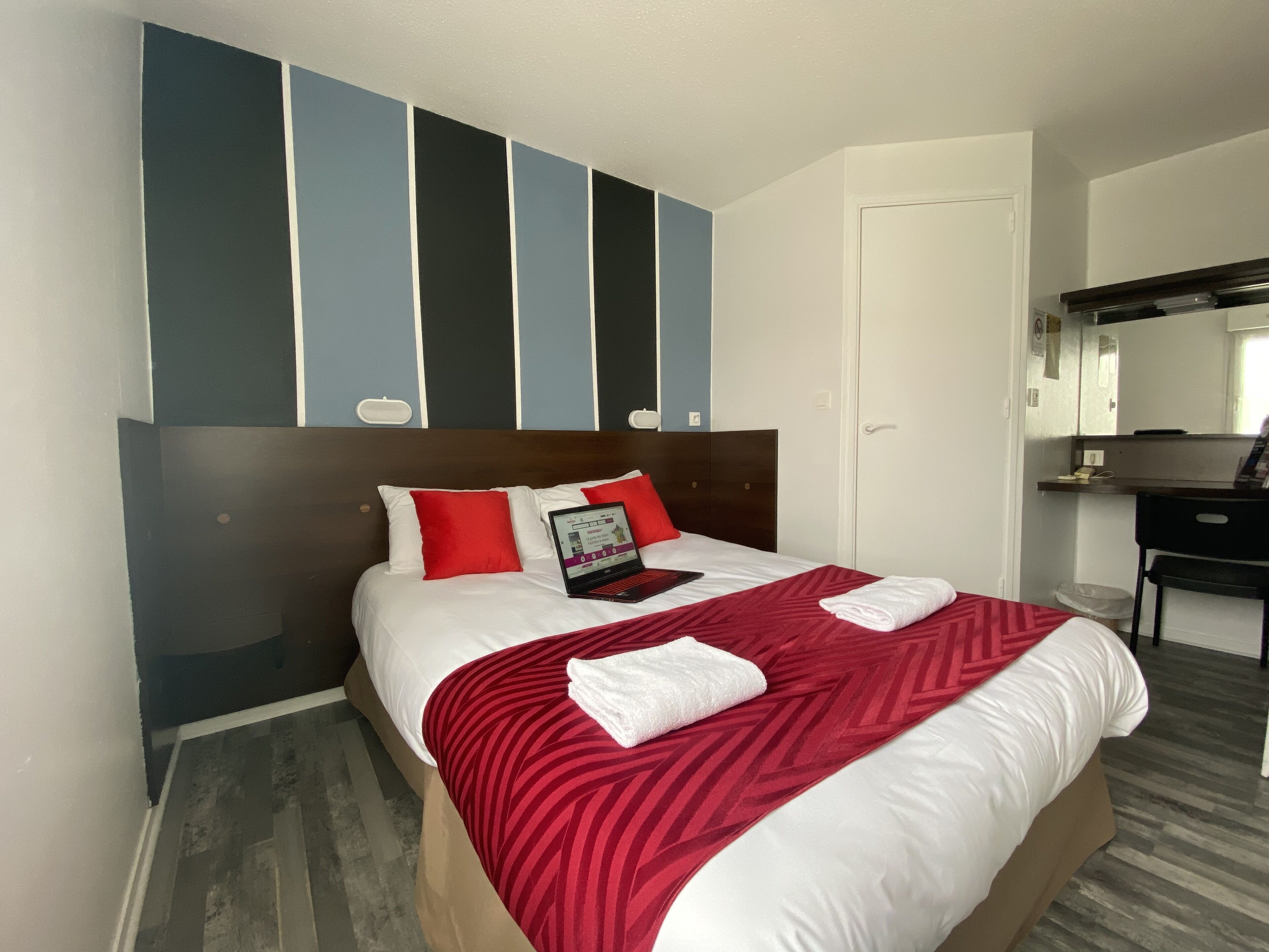 A hotel room with a bed, a desk, and a mirror.
