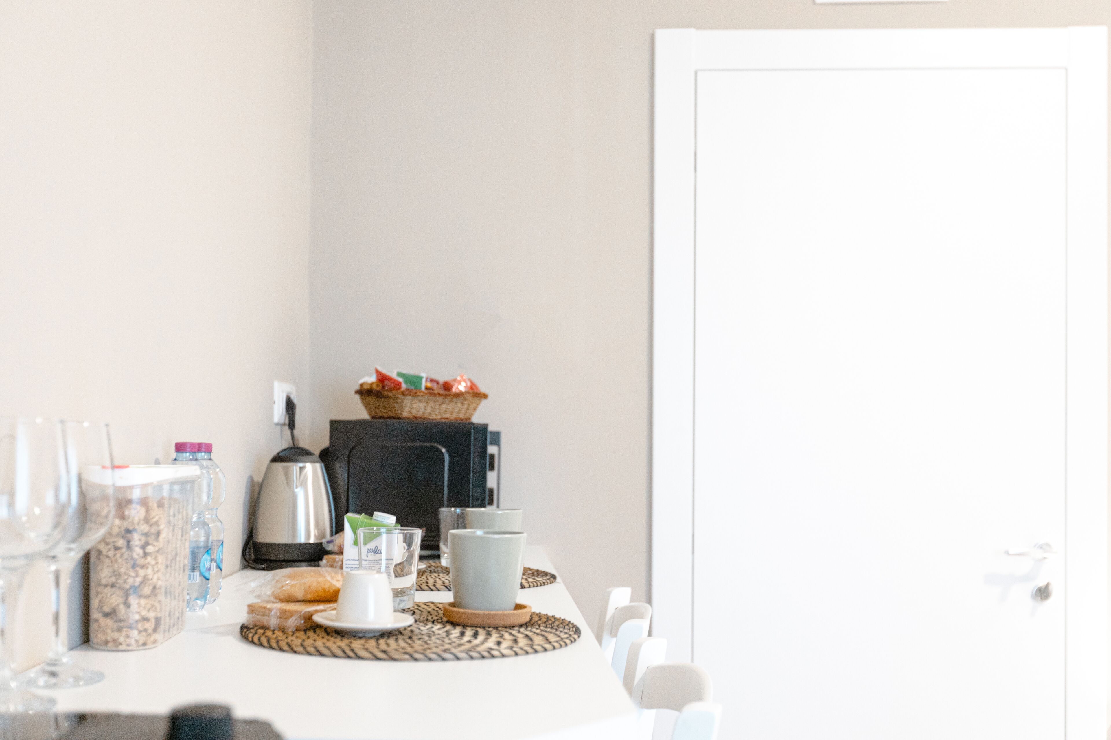 A breakfast table with a coffee maker, a basket of fruit, and various breakfast items.