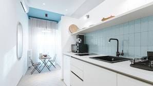 Una cocina moderna con armarios blancos, un lavamanos negro y un salpicadero de azulejos azules.