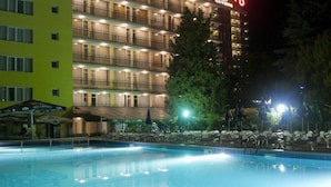 Un hotel con varios balcones y una piscina al frente.