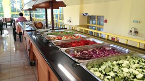 Un bufé con diversas opciones de comida, incluyendo verduras y ensaladas, en un ambiente interior bien iluminado.