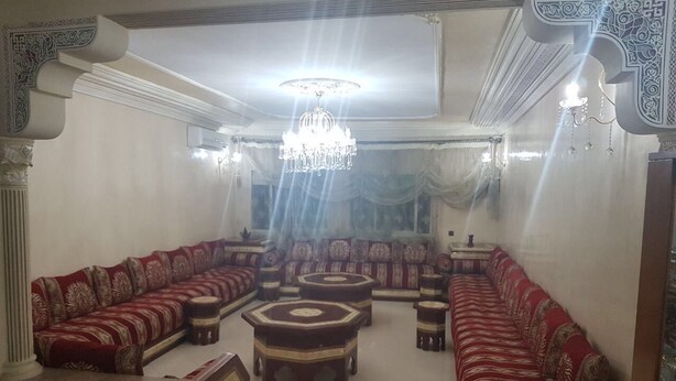 A traditional living room with a sofa set, ottomans, and a chandelier. - Apartment 3 Rooms city center Marmoucha (Fes)