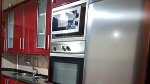 A kitchen with red cabinets, a stainless steel refrigerator, a microwave, and an oven. - Apartment 3 Rooms city center Marmoucha (Fes)