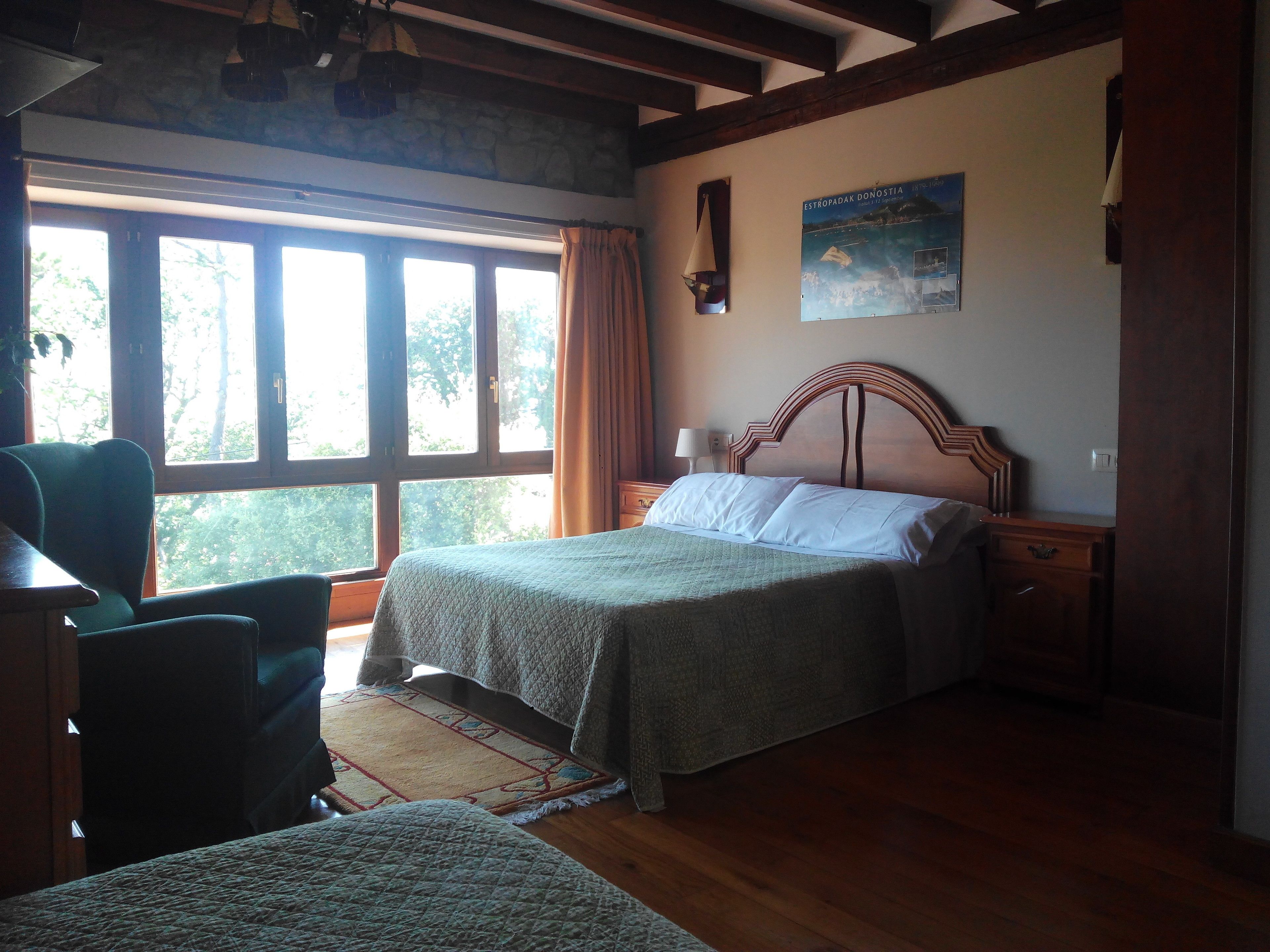 Une chambre à coucher avec un lit, une chaise, une table de chevet et une affiche accrochée au mur.