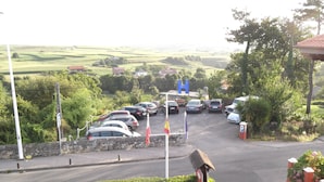 A parking lot with several cars, a stone wall, and a flagpole with flags.