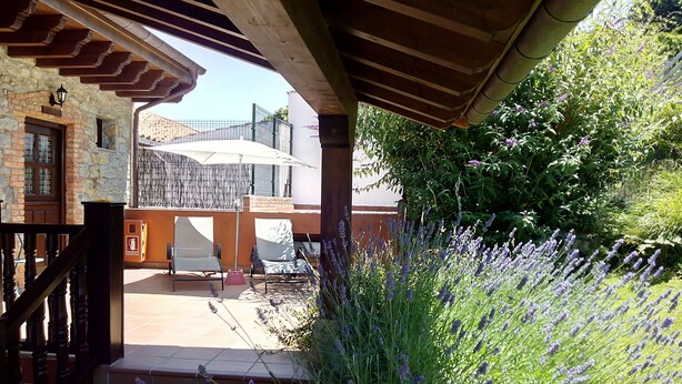 A covered outdoor area with a stone wall, a wooden staircase, and a seating area with a table and chairs.