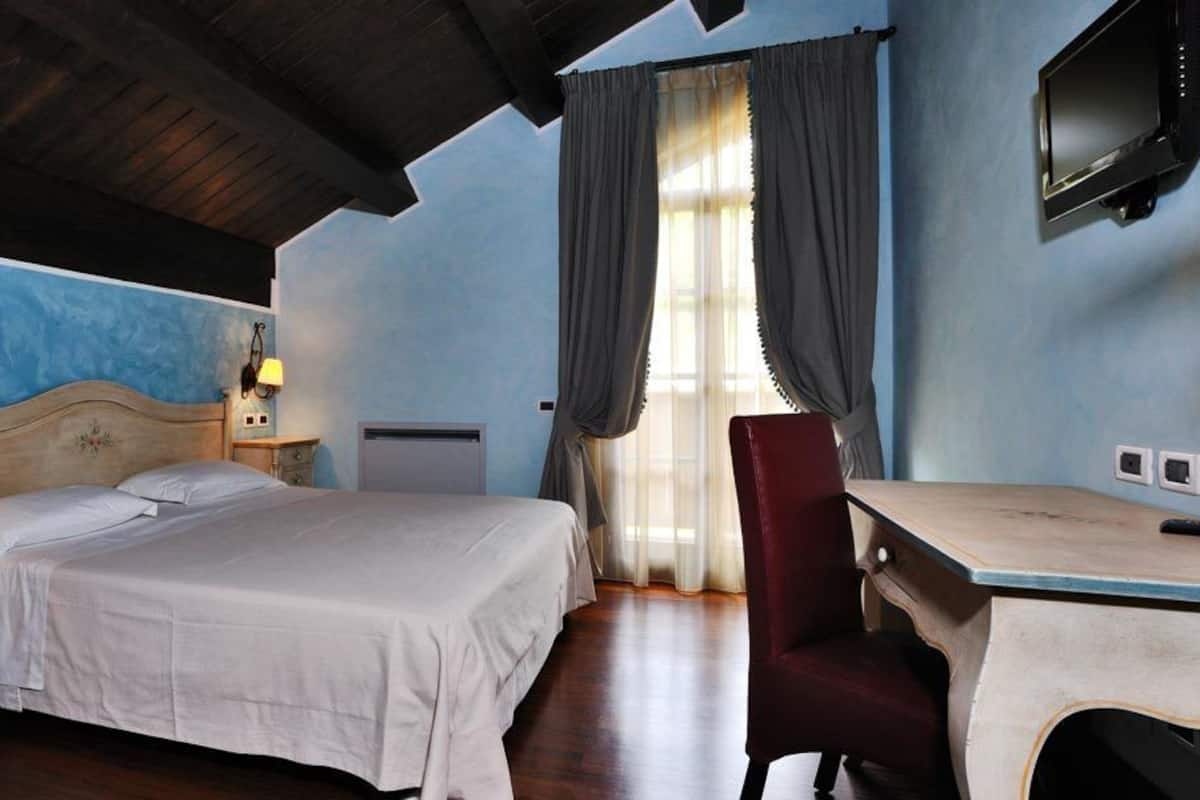 A bedroom with a bed, bedside tables, a desk, and a chair.