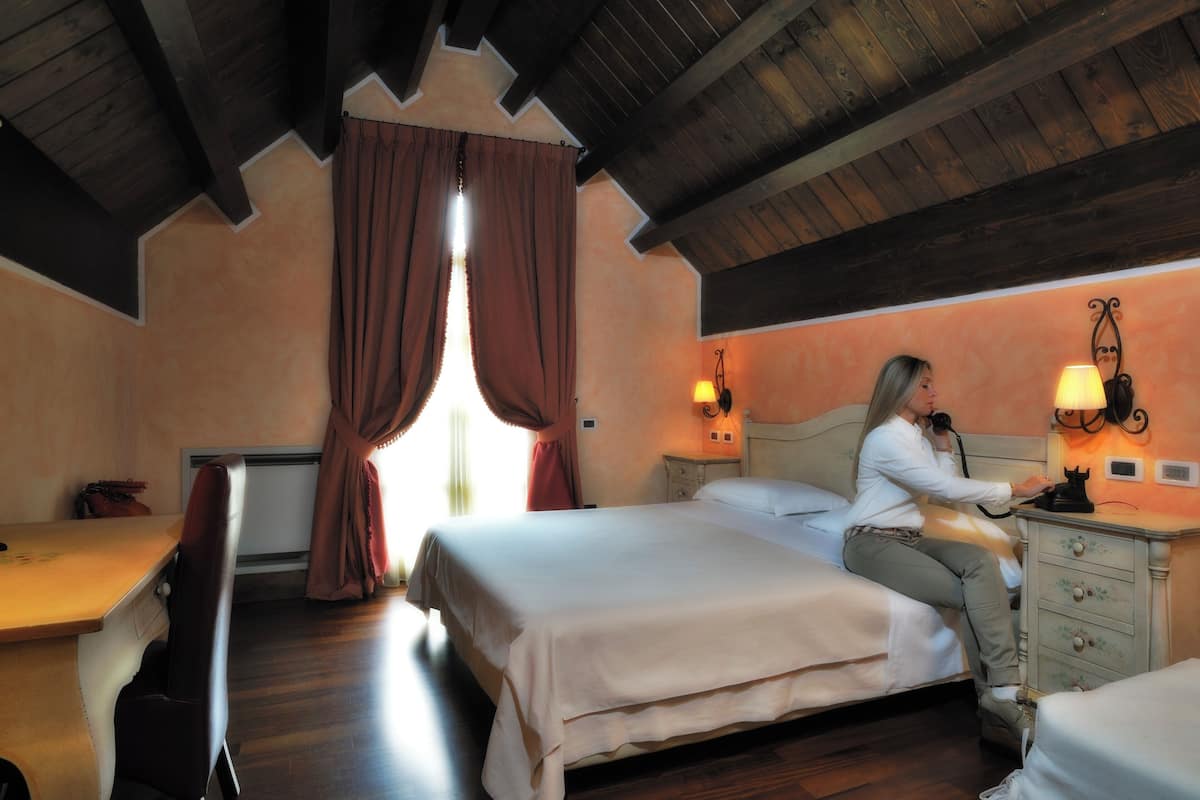 A bedroom with two beds, a desk, and a dresser.