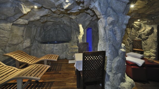 A spa area with wooden loungers, a blue door, and a stone wall. - Hotel Villa Danilo (Gamberale)