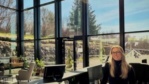 Una moderna zona de recepción con amplios ventanales, un mostrador de información y vistas al exterior.