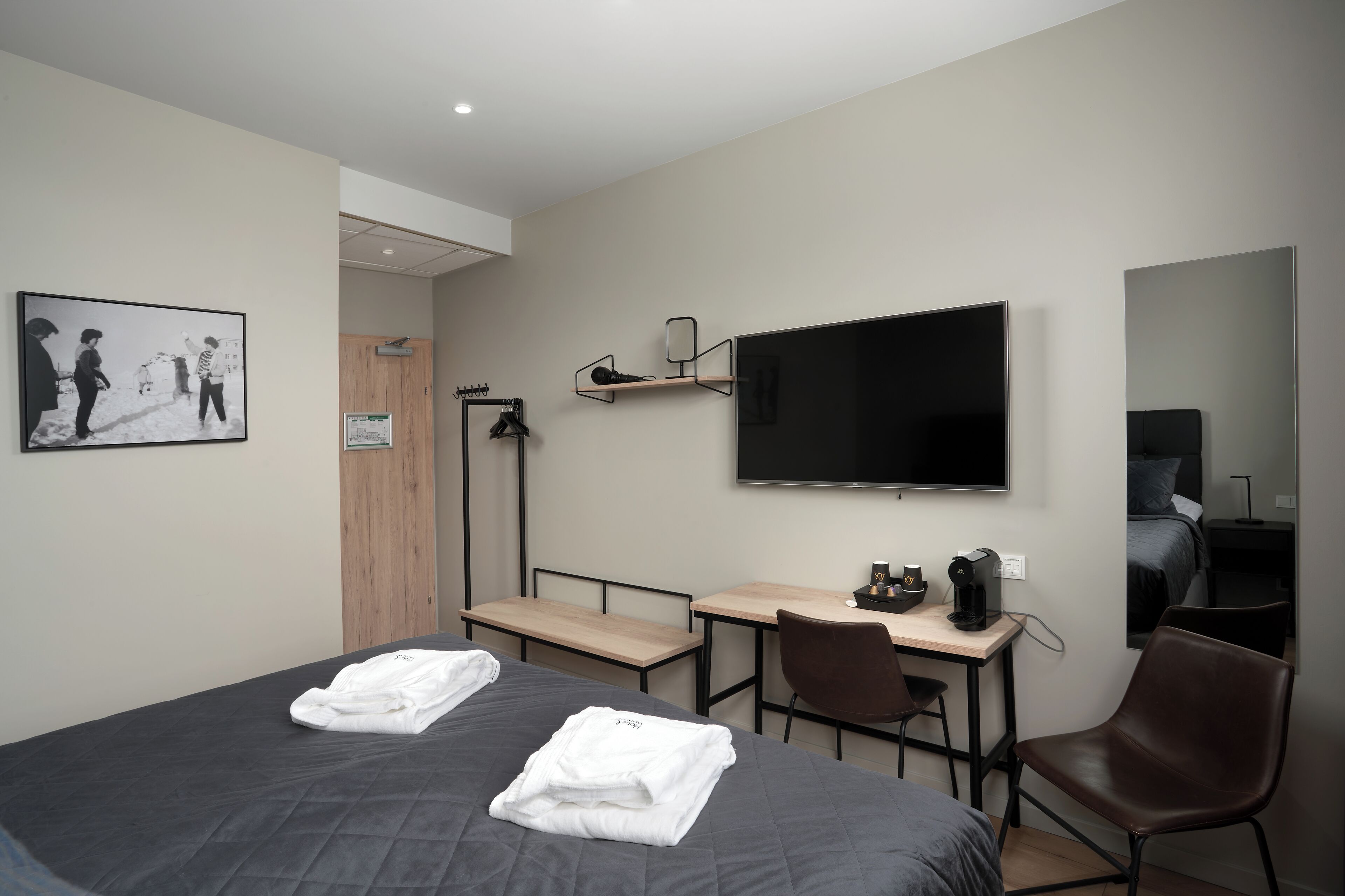Ein modernes Hotelzimmer mit einem großen Bett, einem Schreibtisch mit Stuhl, einem Flachbildfernseher und einem Kleiderschrank.