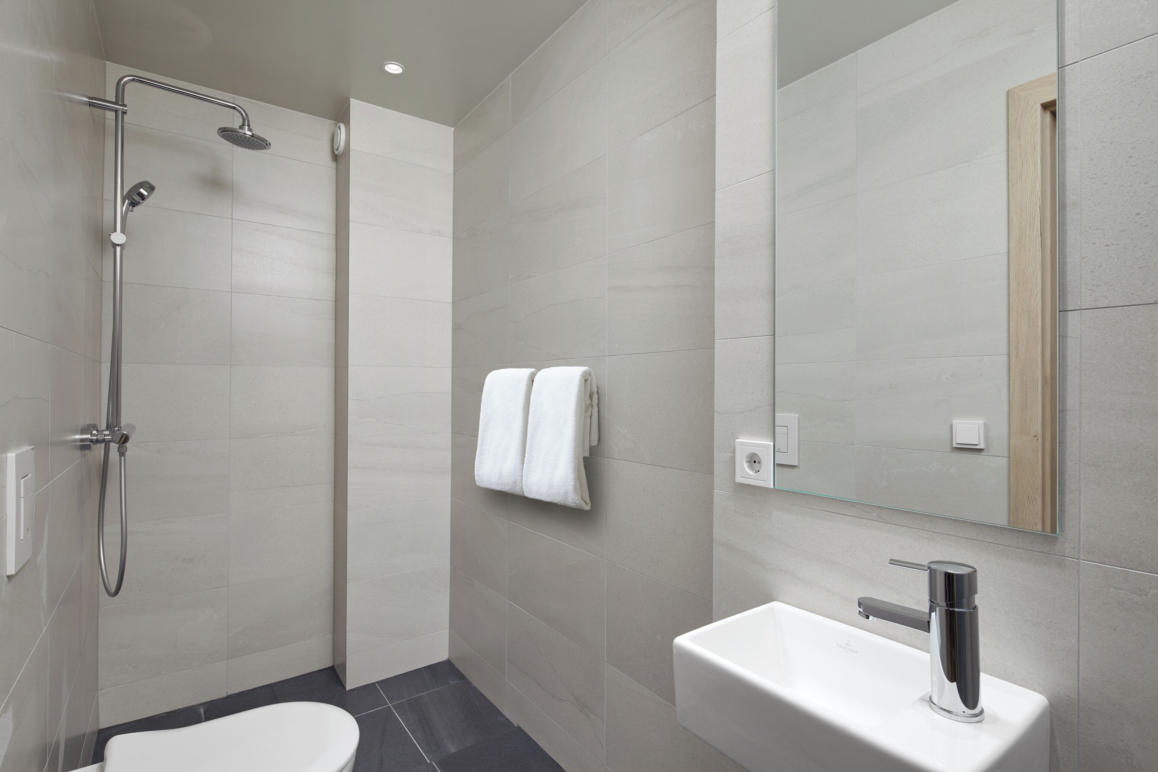 A modern bathroom with a shower, toilet, and sink.