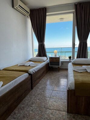 A hotel room with two beds, a small table, and a view of the sea. - Varshava Hotel (Golden Sands)