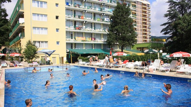 A swimming pool area with multiple levels of balconies, lounge chairs, and umbrellas. - Varshava Hotel (Golden Sands)