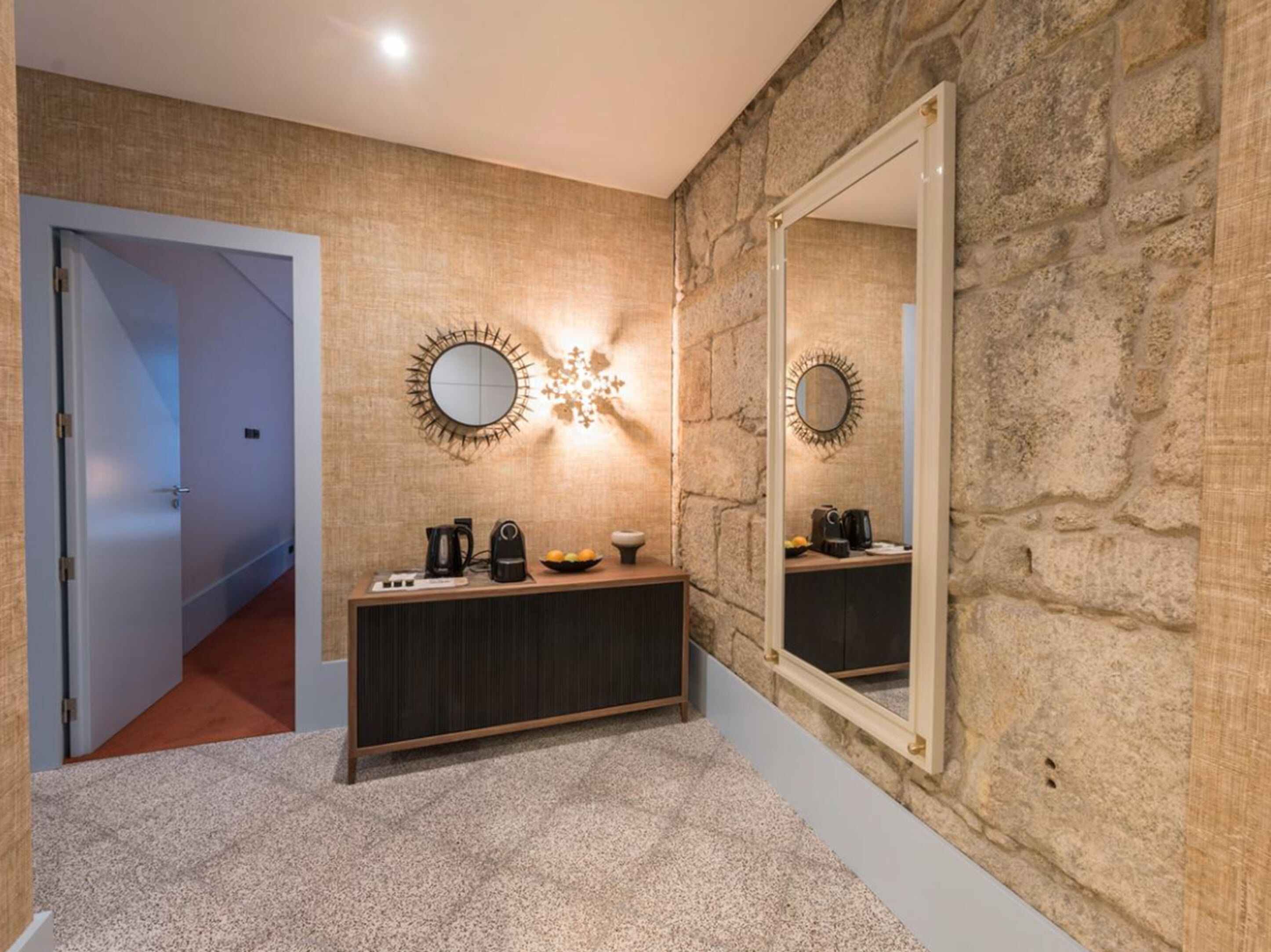 A modern bathroom with a stone wall, a large mirror, and a vanity with a sink and countertop.