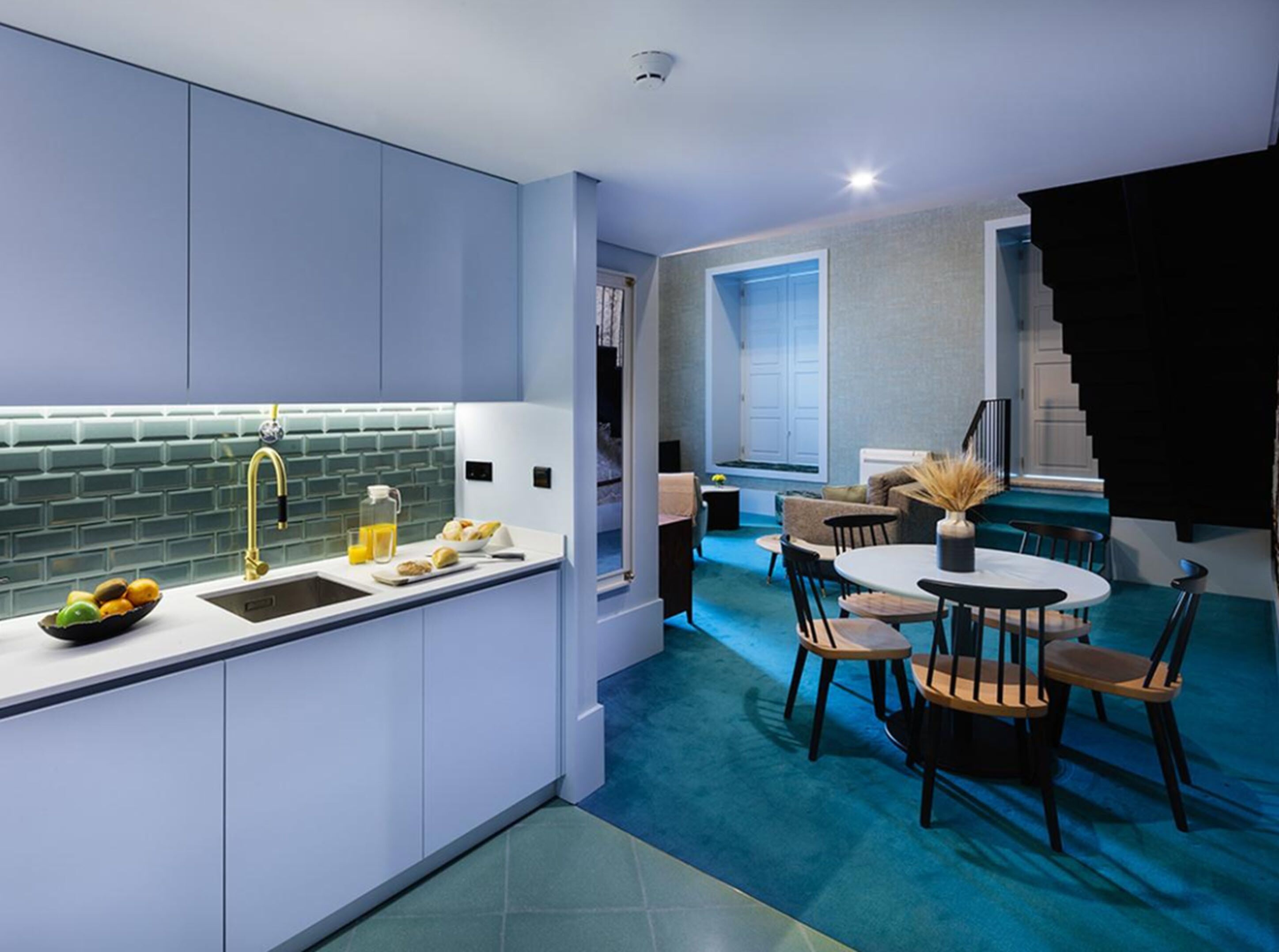 A modern kitchen with a sink, countertop, and a dining area with a table and chairs.