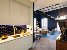 A modern kitchen with white cabinets, a blue-tiled backsplash, and a yellow faucet.