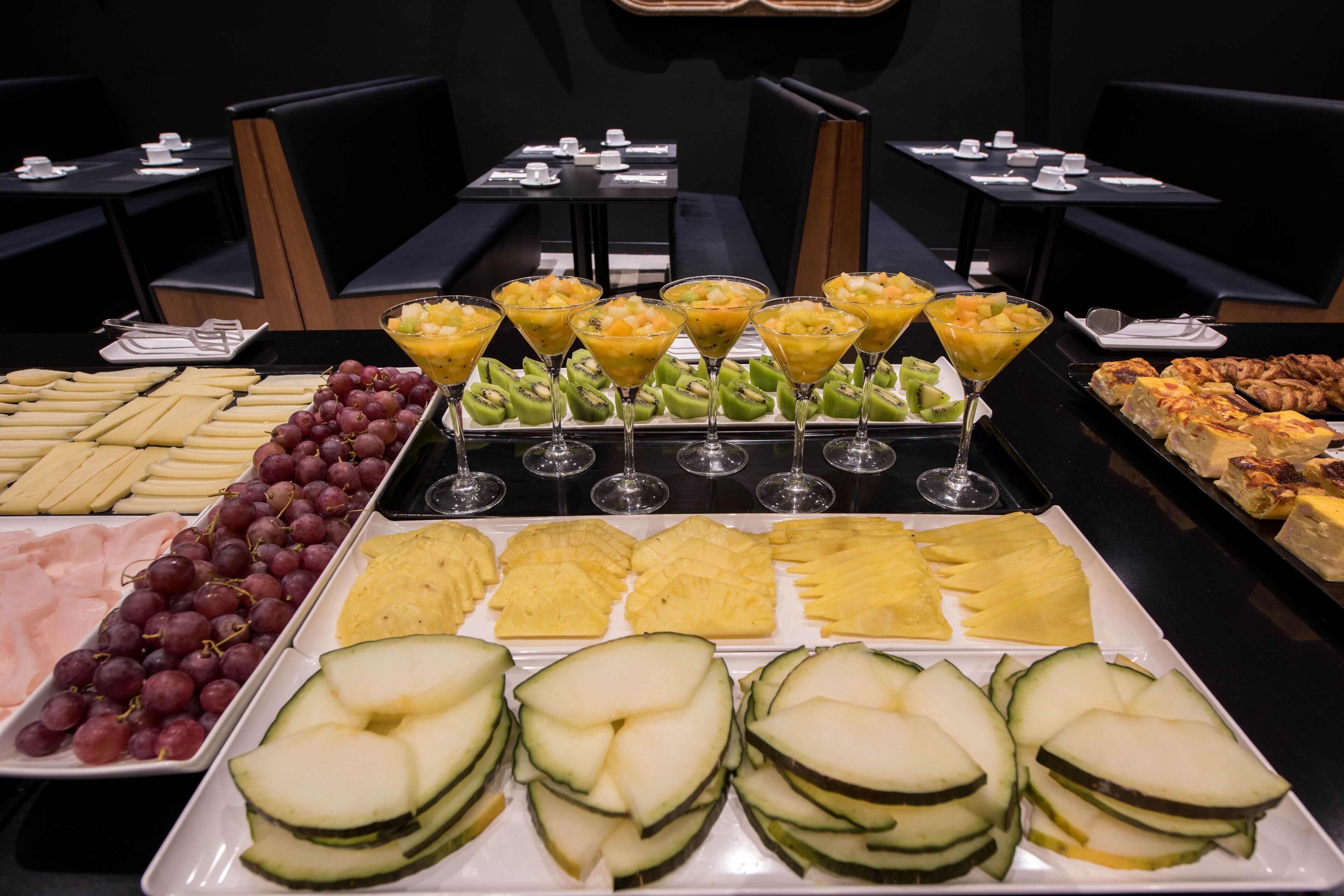 Un buffet proposant une variété de fruits, de fromages et un assortiment de boissons.