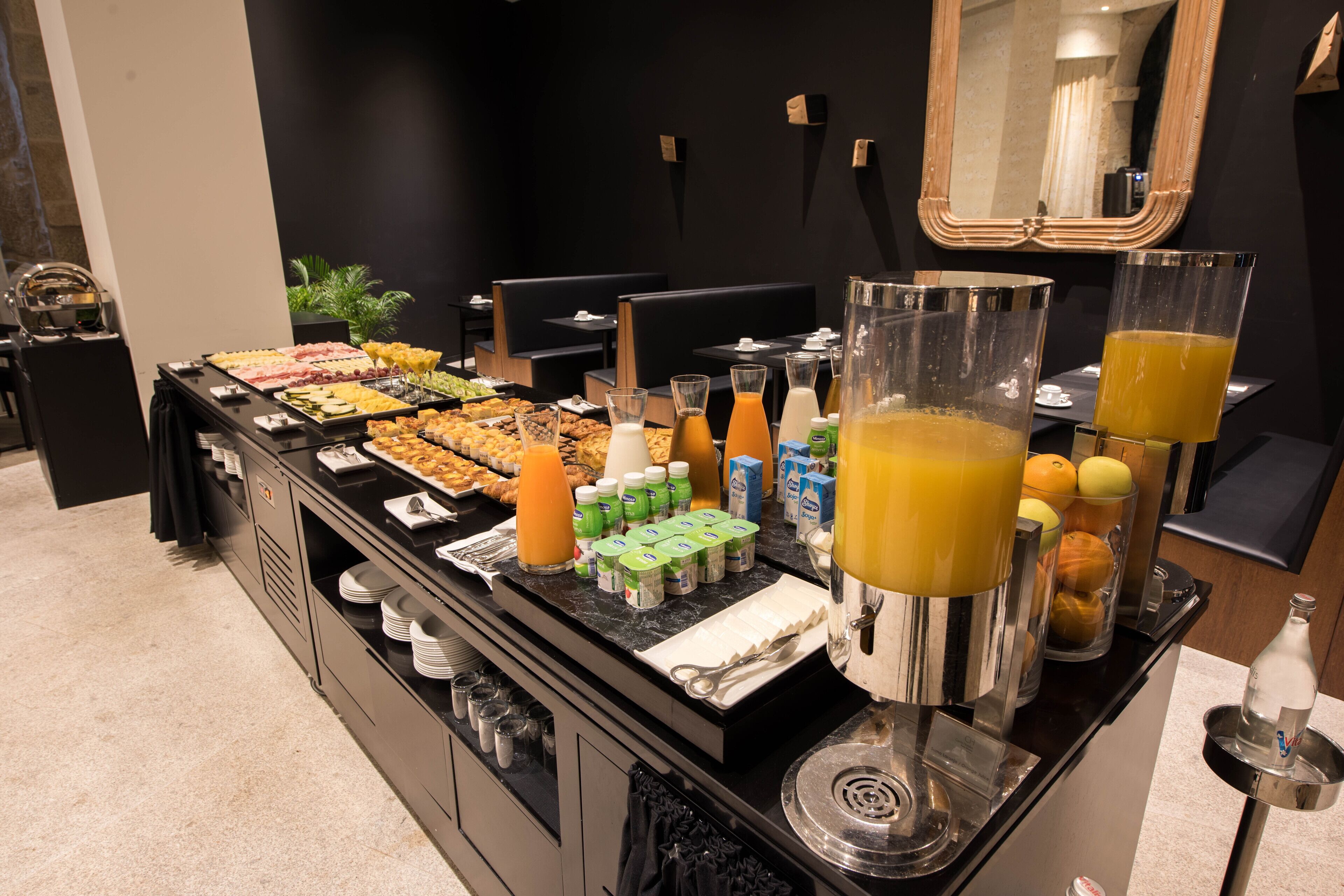 A buffet setup with various food items, beverages, and condiments.