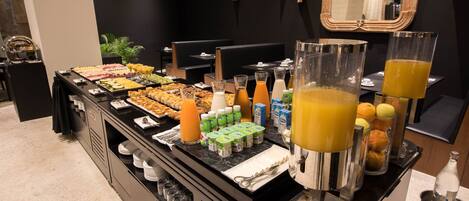 A buffet setup with various food items, beverages, and condiments.